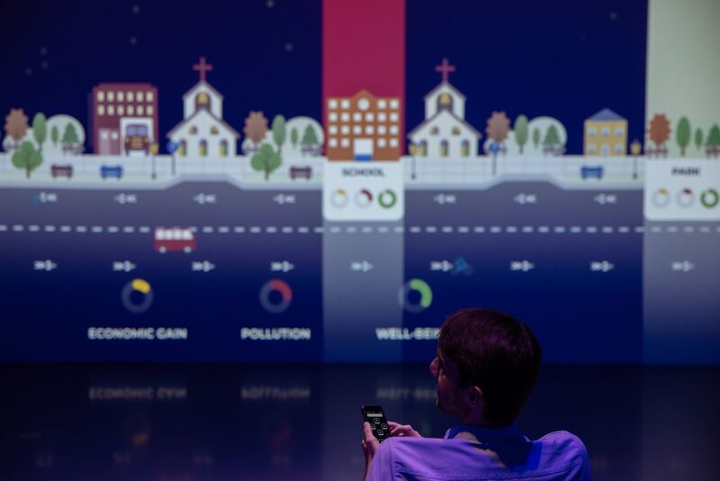 A visitor steering the game from a phone in front of the projected street